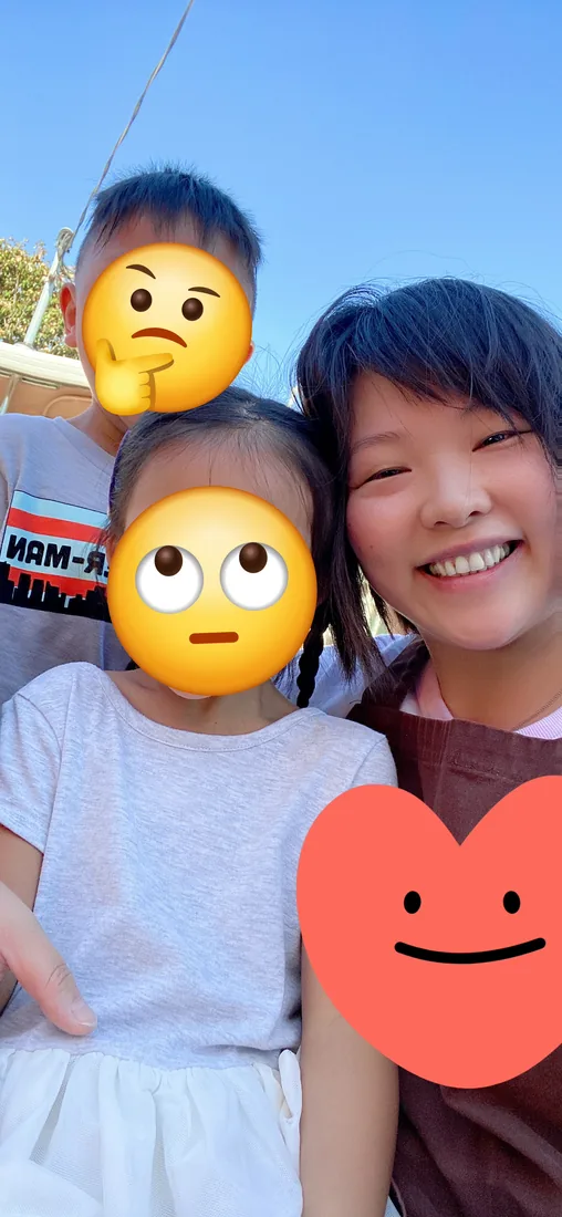 Lia outside on a sunny day with two young children she cared for before opening Lia's Preschool